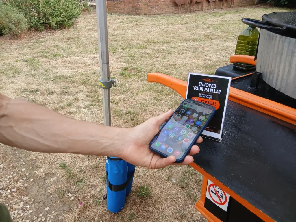 Customer tapping a Just Tap Review Google review stand with a smartphone